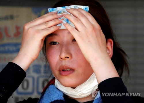 일본 오카야마 현에서 한 자원봉사자가 얼굴에 아이스팩을 대고 더위를 식히고 있다. [로이터=연합뉴스]