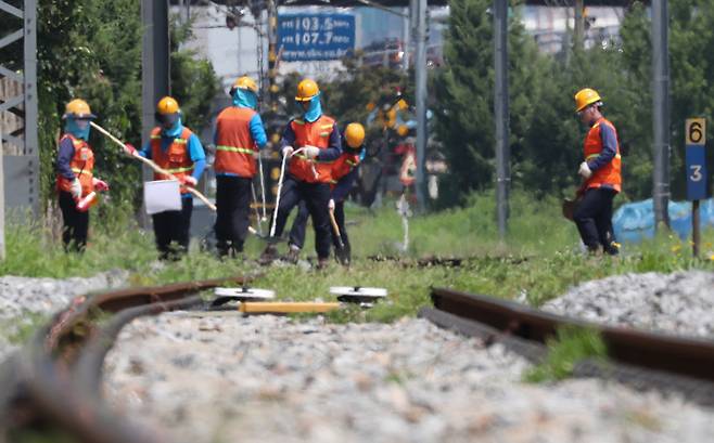 전국이 가마솥 불볕더위로 펄펄 끓던 지난 19일 서울 용산구 서빙고역 코레일 직원들이 뜨거운 태양에 달궈진 선로 위에서 도상자갈을 보충하고 있다. [뉴스1]