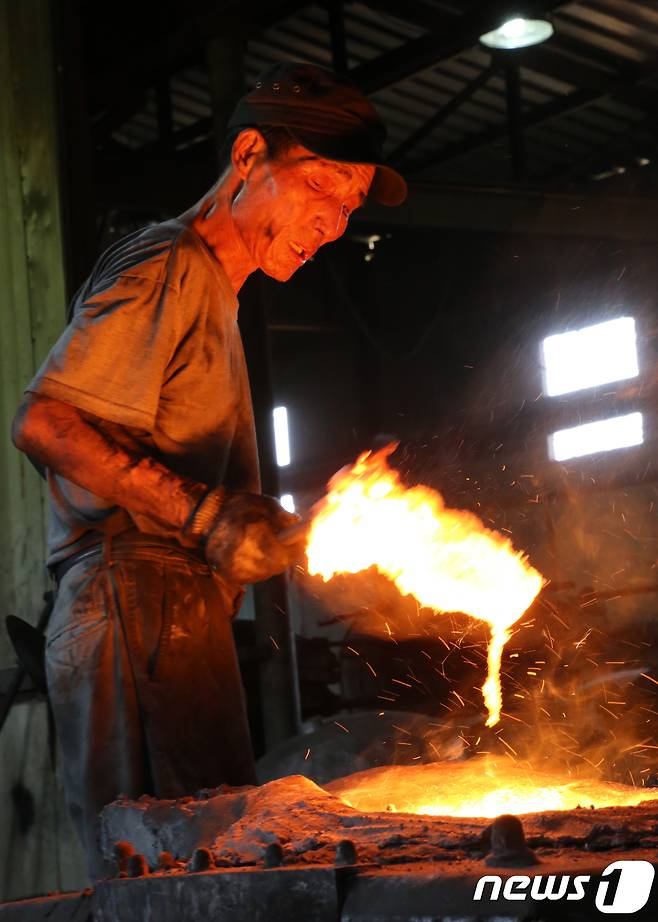 29일 경북 구미시 고아읍 사랑채 가마솥공장에서 50년 베테랑인 유용만(70)씨가 1500도 용광로에서 불순물을 걷어내고 있다.2018.7.29/뉴스1 © News1 정우용 기자