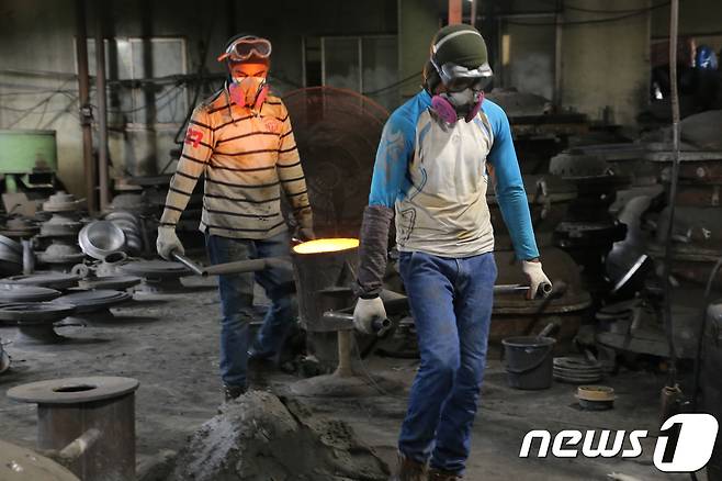29일 경북 구미시 고아읍 사랑채 가마솥공장에서 스리랑카에서 온 락마와 쟈스카씨가 1500도 용광로에서 녹인 쇳물을 담은 70여Kg의 쇳물통을 옮기고 있다. 2018.7.29/뉴스1 © News1 정우용 기자