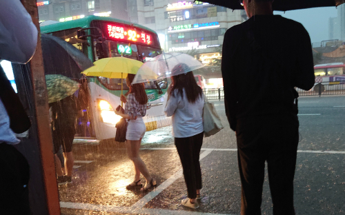 수도권지역에 폭우가 쏟아진 28일 오후 경기도 고양시 대화역 버스정류장에서 시민들이 우산을 쓴 채 버스를 타기 위해 이동하고 있다.