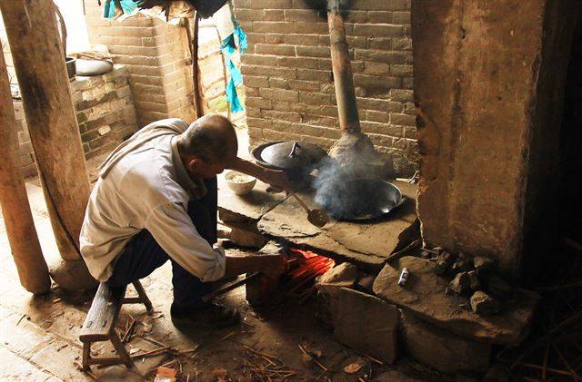 면을 삶기 위해 아궁이에 불을 피우는 할아버지.