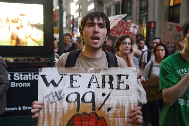 2011년 9월 미국 뉴욕의 금융 중심지 월스트리트에서 극단적인 빈부 격차와 금융자본의 탐욕에 항의해 벌어진 ‘오큐파이(점령하라) 운동’에 참가한 한 시민이 ‘우리가 99%다’라고 쓰인 팻말을 들어보이고 있다.   위키미디어 커먼스
