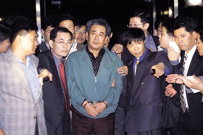 김근태 초대 민청련 의장을 고문한 이근안(가운데)씨가 1999년 11월 검찰에 송치되고 있다. 1988년부터 11년 가까이 도망 다니다 자수한 이씨는 7년의 실형을 살고 나온 뒤 목사로 변신했다. <한겨레> 자료사진