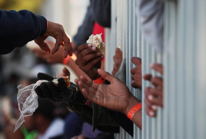 캐러밴 이민자들이 18일(현지시간) 멕시코 티후아나 임시 보호소에서 음식을 받고 있다. [로이터=연합뉴스]