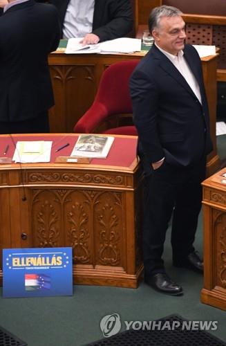 빅토르 오르반 헝가리 총리가 12일(현지시간) 노동법 개정안 처리를 앞두고 의회에 출석했다. 오르반 총리 옆에는 '저항, 민주주의'라고 적힌 플래카드가 놓여 있다. [AFP=연합뉴스]