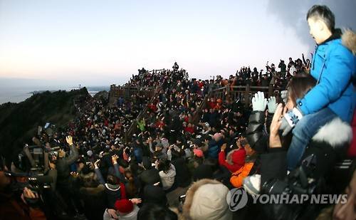 "해야 솟아라!" (서귀포=연합뉴스) 새해 첫날인 1일 제주도 서귀포시 성산읍 성산일출봉 정상을 찾은 제주도민과 관광객이 "해야 솟아라!"를 외치며 손을 흔들고 있다. [연합뉴스 자료사진]