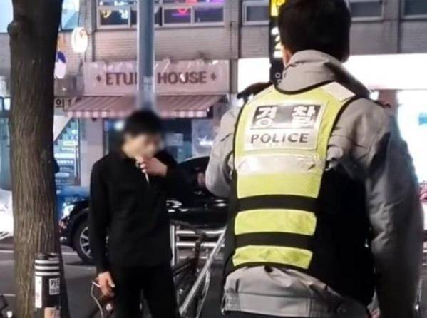 지난 13일 오후 7시쯤 ‘암사역 칼부림’ 피의자 한씨가 암사역 3번 출구 앞에서 커터칼을 든 채 손가락에 묻은 피를 빨며 경찰과 대치하고 있는 모습. /유튜브 캡처