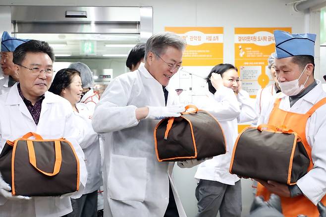 문재인 대통령이 1일 오전 서울 관악구 행복도시락 사회적협동조합 관악센터에서 최영남 나눔공동체 대표와 함께 도시락 포장을 하고 있다. 이날 문 대통령은 설 명절을 맞아 행복도시락 사회적협동조합 관악센터 ‘나눔공동체’와 함께 취약계층 청소년 가정에 도시락을 배달했다. [사진 청와대]