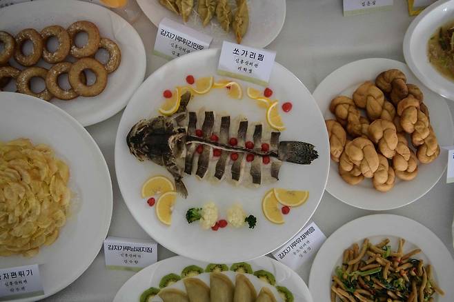 북한 신흥산려관의 요리사들이 함께 차려낸 한상차림. 쏘가리찜을 비롯해 감자가루를 활용한 튀긴 만두, 유채볶음, 감자 편튀기 등 다양한 음식을 선보이고 있다. 사흘간 북한 평양에서 열린 전국 요리 경연대회에 출품된 음식으로 13일 촬영했다. 평양/AFP 연합뉴스