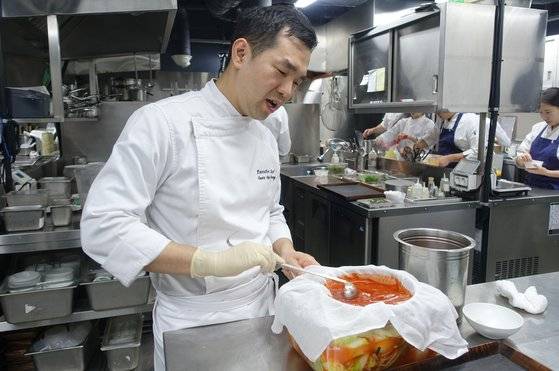 권우중 셰프가 양념을 풀어 우린 꿩육수를 베 보자기로 거르면서 김치에 붓고 있다.