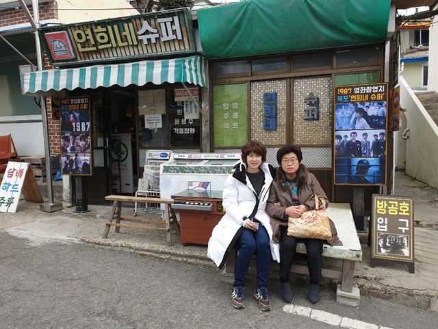 서울에서 연희네슈퍼를 방문한 노혜정씨가 남녀 주인공이 앉은 평상에 엄마와 함께 앉아 추억을 만들고 있다.