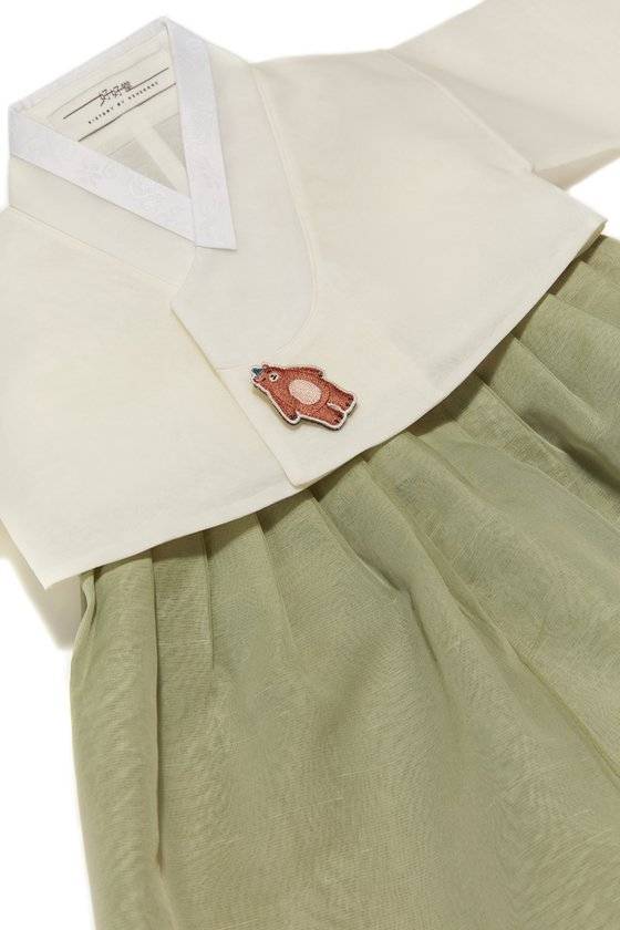 운백색 저고리에 두록색 치마를 매치한 노방 소재 여아 한복. 옷고름 대신 동물 브로치를 달았다. [사진 호호당]