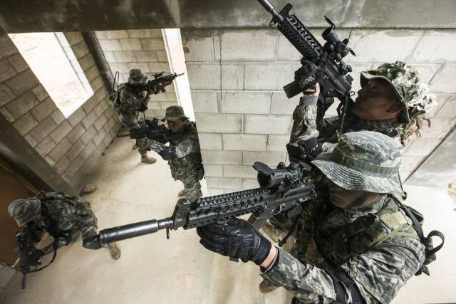 K1A 소총 개량형(조준경 등을 부착할 수 있는 피카트니 레일과 신축형 개머리판 채용)으로 무장한 특전사 작전요원들이 시가지 전투 훈련에서 건물을 수색하고 있다. 특전사에 새로 보급될 개량형은 이보다 더 진전된 모델로 알려졌다.