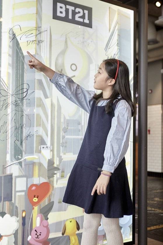 맹서후 학생기자가 'BT21' 캐릭터, 방탄소년단(BTS) 멤버의 서명이 담긴 모습을 보고 손가락으로 가리키고 있다.