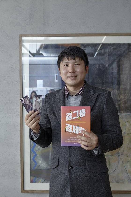 유성운 작가가 자신의 책 '걸그룹 경제학', 소녀시대 멤버 윤아·서현 포토카드를 들어 보였다. 그는 지난 2017년 소녀시대 데뷔 10주년을 맞이해 소녀시대 등 아이돌 그룹의 영향을 데이터로 증명한 책을 펴냈다.