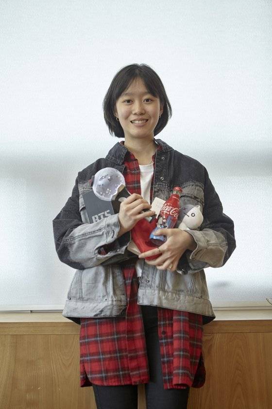 김나연 학생기자가 방탄소년단(BTS) 굿즈를 품에 가득 안아 보였다. 그는 시즌 그리팅 앨범, 응원봉 아미밤, 카페에서 받은 BTS 관련 굿즈, BT21 인형 등 다양한 제품을 갖고 있다.