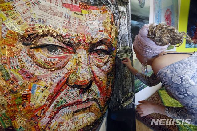 【키예프=AP/뉴시스】우크라이나 작가 다샤 마르첸코가 28일(현지시간) 우크라이나 키예프에 있는 자신의 스튜디오에서 우크라이나 대통령 겸 초콜릿 재벌 페트로 포로셴코의 초상화를 제작하고 있다. 이 작가는 20kg에 달하는 초콜릿을 사서 그 포장지로 포로셴코의 얼굴을 만들었고 초상화의 프레임은 2014년부터 러시아가 지원한 분리주의자들과의 분쟁으로 타격을 입은 우크라이나 동부 지역 전쟁터에서 사용된 4000발의 탄피로 만들었다.포로셴코는 오는 31일 우크라이나 대선에서 대통령 연임에 도전한다. 2019.03.29.