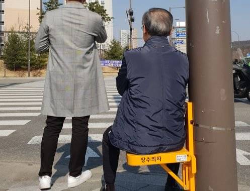 지난달 29일 경기 남양주시 별내동 별사랑마을 횡단보도 앞에 시범 설치된 장수의자. 한 노인이 앉아서 신호를 기다리고 있다. 남양주경찰서는 1일 오후 1시 별내동에 총 60개의 의자를 설치한다.［사진 별내파출소］
