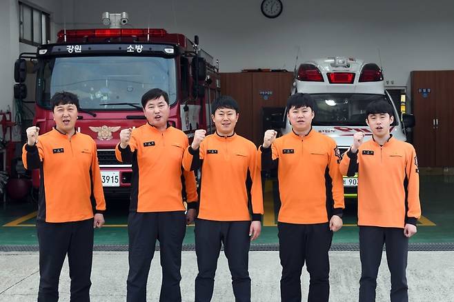 간성119안전센터 팀원들이 소방차 앞에서 파이팅을 외치고 있다. 사진 좌로부터 윤재준 소방장(진압대원), 윤 팀장, 서경훈 소방사(진압대원), 최원용 소방교(구급대원), 윤병국 소방사(구급대원)