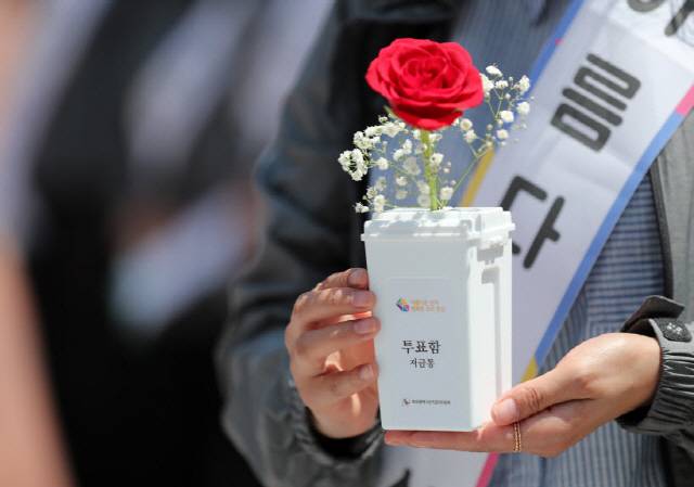 지난해 성년의 날, 부산시선관위 관계자들이 모형 투표함에 장미꽃을 담아 대학생들에게 나눠주며 지방선거 투표참여 캠페인을 하고 있다.- 연합뉴스