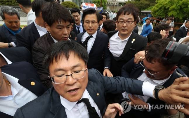 황교안 자유한국당 대표가 18일 오전 제1야당 대표로서 국가보훈처의 공식초청을 받아 5·18 39주기 추도식장에 입장하려는 과정에서, 일부 단체 관계자가 넥타이를 낚아채 추도의 의미를 담은 검은 넥타이가 크게 비뚤어져 있다. 이헌승 대표비서실장이 앞에서 길을 뚫고 있다. ⓒ연합뉴스