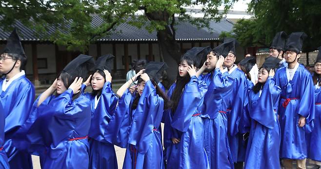 급제자들이 갑자기 불어온 강한 바람에 머리에 쓴 유건을 붙잡고 있다. 우상조 기자