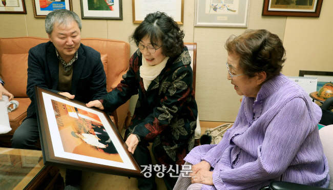 지난해 3월 서울 동교동 김대중 전 대통령 자택에서 경향신문 이기수 편집국장(왼쪽)이 이희호 여사에게 지난 2010년 이 여사의 모습이 담긴 사진을 선물하고 있다.가운데는 유시춘 작가.정지윤기자
