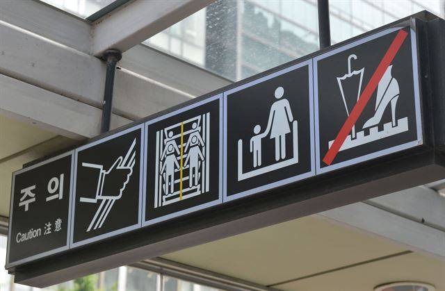 홍대입구역 에스컬레이터 앞에 고객 안전 주의 픽토그램이 게시돼 있다. 이 중 어린이 보호를 위해 손을 잡을 보호자는 대부분 여성으로 묘사된다.