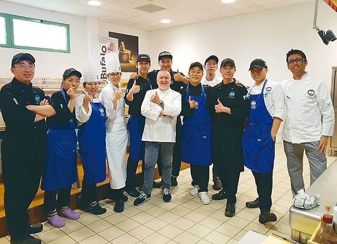 한국인 동기들이 외국인을 위한 이탈리아 요리학교 실습실에서 초청 셰프와 기념사진을 찍고 있다. 검은 모자를 쓴 학생 8명이 한국인 동기다.