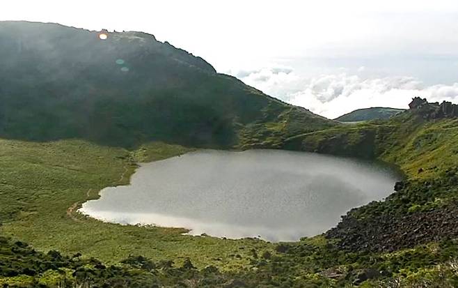 24일 오후 제5호 태풍 다나스와 장마전선 영향으로 많은 비가 내려 만수가 된 제주 한라산 백록담이 아름다운 비경을 뽐내고 있다. [사진 한라산 국립공원 CCTV 영상 캡처=뉴시스]