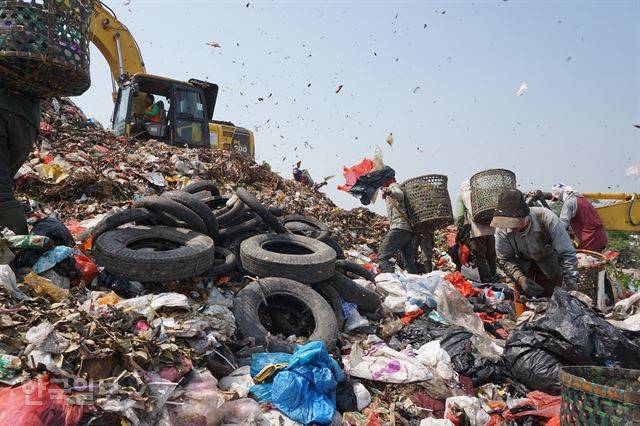 동남아 최대 쓰레기산인 인도네시아 반타르 그방 매립지에서 굴착기가 위로 옮기던 쓰레기가 떨어져 눈처럼 흩날리는 장면.