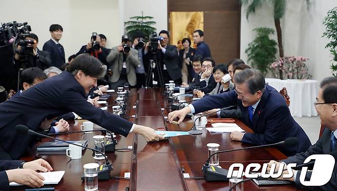 문재인 대통령이 지난해 1월22일 청와대 여민관에서 열린 수석보좌관회의에서 모두발언을 마친 후 조국 민정수석으로부터 과자를 받고 있다. (청와대 제공) 2018.1.22/뉴스1 © News1 이광호 기자