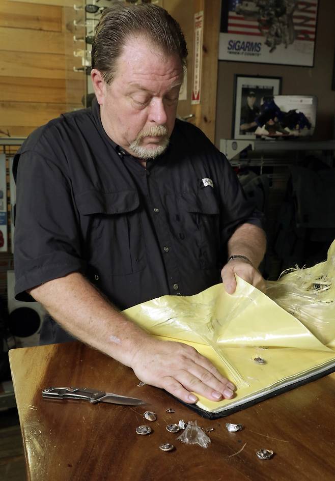 스티브 나레모어가 9일(현지시간) 휴스턴의 한 사격 연습장에서 방탄 가방에 사격을 마친 뒤, 탈착식 탄도 보호막을 뚫지 못하고 박힌 총알을 꺼내고 있다. [AP=연합뉴스]