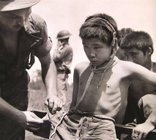 앳된 얼굴의 한인 포로가 뉴기니 섬에서 미군에 붙잡힌 후 몸 수색을 당하고 있다. 1943년 1월 2일. 국사편찬위원회 제공ㆍNARA 소장