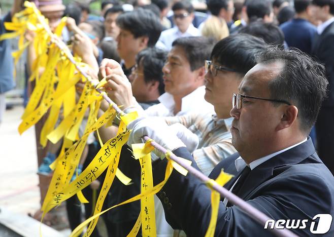 17일 오전 청주고인쇄박물관에 위치한 고(故) 민준영(당시 36세)·박종성 대원(당시 42세)의 추모비 앞에서 유가족 등이 노란 리본을 달고 있다. 2019.8.17/뉴스1 © News1 김용빈 기자