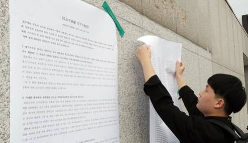 부산대 재학생이 23일 오후 부산대 정문 인근 담벼락에 조국 법무부 장관 후보자 딸 특혜와 관련된 의전원 교수 2명과 대학 측에 해명을 요구하는 대자보를 붙이고 있다. 연합뉴스