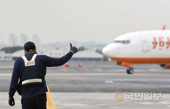 지상조업사 직원이 수신호로 비행기의 계류장 진입을 돕고 있다.