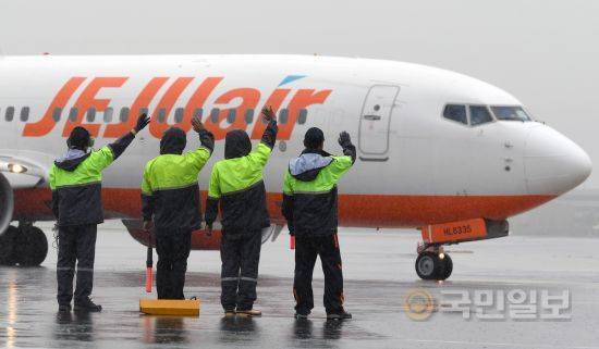 JAS 직원들이 비행기의 이륙준비를 마치고 승객들에게 손을 흔들고 있다.