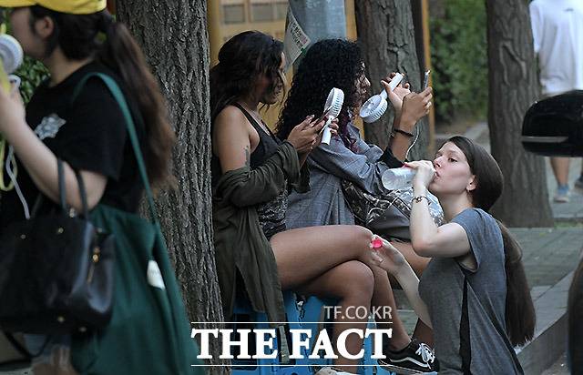 더운 날씨에도 불구하고 손선풍기와 물을 마시며 연예인을 기다리는 해외팬들.