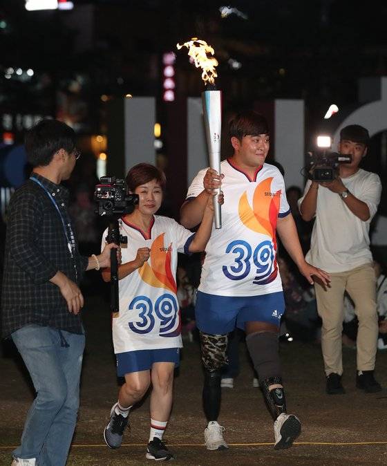 지난달 29일 서울 중구 서울광장에서 장애인체전 성화 봉송 마지막 주자인 방송인 김미화와 하재헌 전 육군 중사가 봉송을 하고 있다. [뉴시스]