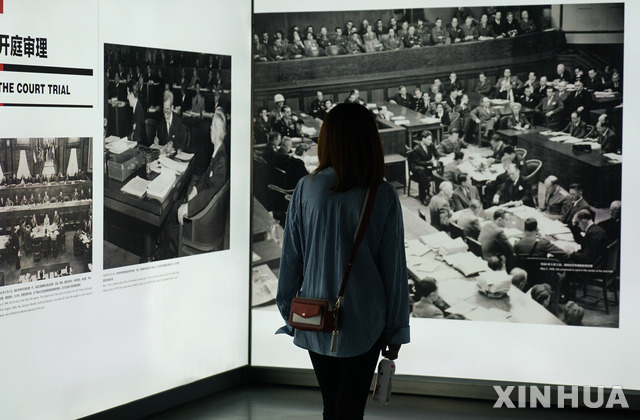 【난징(중국)= AP/뉴시스】 지난 9월 18일 난징에서 열린 난징대학살 71주기 기록사진 전시회에서 한 관람객이 전쟁후의 도쿄 일본군 전범 재판에 관한 사진을 들여다 보고 있다.  이 전시회는 2020년 3월까지 계속된다.