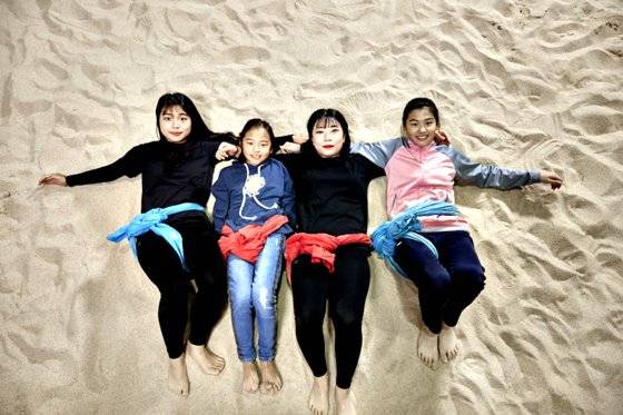 (왼쪽부터)오 선수, 가영 학생, 정 선수, 유림 학생이 용인 씨름전용경기장 모래판 위에 누워 카메라를 응시했다.