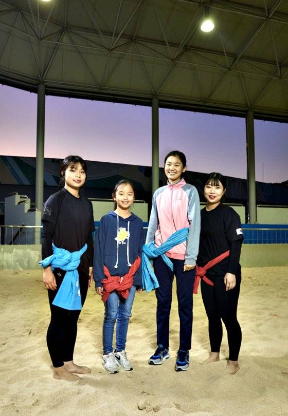 (왼쪽부터)오채원 선수, 가영·유림 학생, 정하린 선수가 모래판 위에서 샅바를 맨 후 카메라를 응시했다.