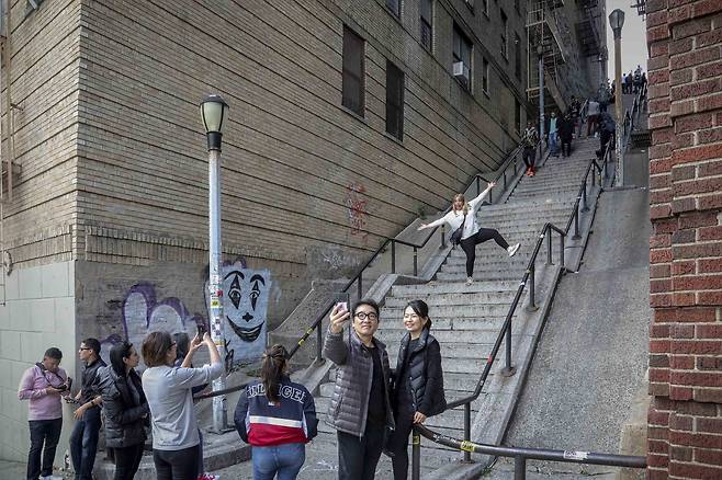 28일(현지시간) 미국 뉴욕 브롱크스 웨스트 167번가의 계단에서 관광객들이 영화 조커 속 한 장면을 패러디하며 인증사진을 찍고 있다. [AP=연합뉴스]