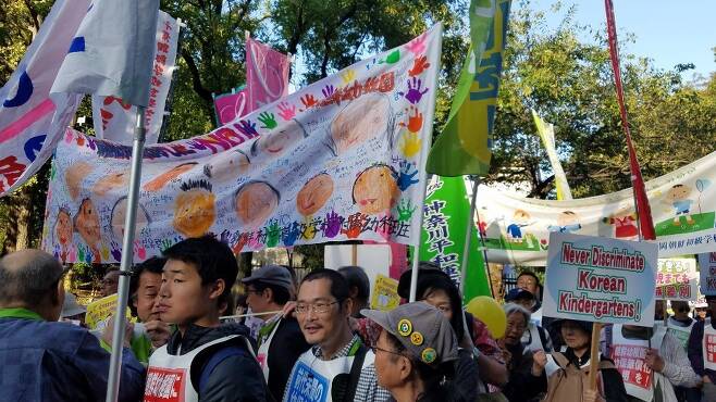 조선학교 유아교육 무상화 제외 조처에 반대하는 재일동포와 일본 시민들이 2일 거리 행진 시위를 하고 있다. 조선학교 유치원 아이들이 그린 그림으로 만든 펼침막도 보인다.
