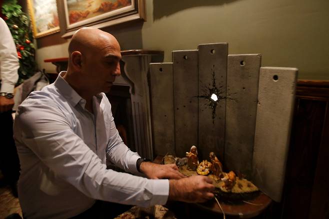 팔레스타인 베들레헴에 있는 ‘월드 오프(Walled Off) 호텔’의 매니저 위삼 살사가 22일(현지시간) 영국 그래피티 작가 뱅크시의 작품 ‘베들레헴의 상흔’을 전시하고 있다. &nbsp;베들레헴 | 로이터연합뉴스