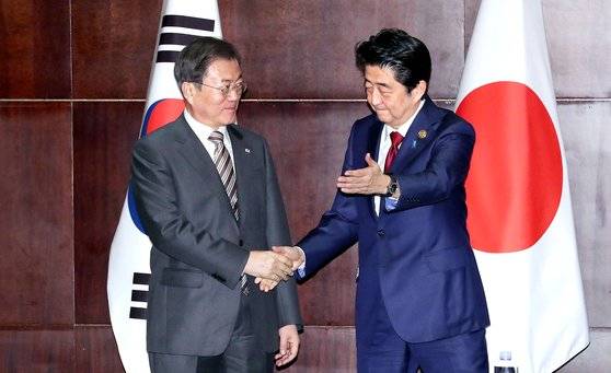 문재인 대통령(왼쪽)과 아베 신조 일본 총리가 24일 중국 쓰촨성 청두 세기성 샹그릴라호텔에서 열린 정상회담에서 악수하고 있다. 이날 중국 공산당 기관지 인민일보는 1면 상단에 한·중 정상회담을, 하단에 중·일 정상회담 소식을 각각 게재했다. [청와대사진기자단]