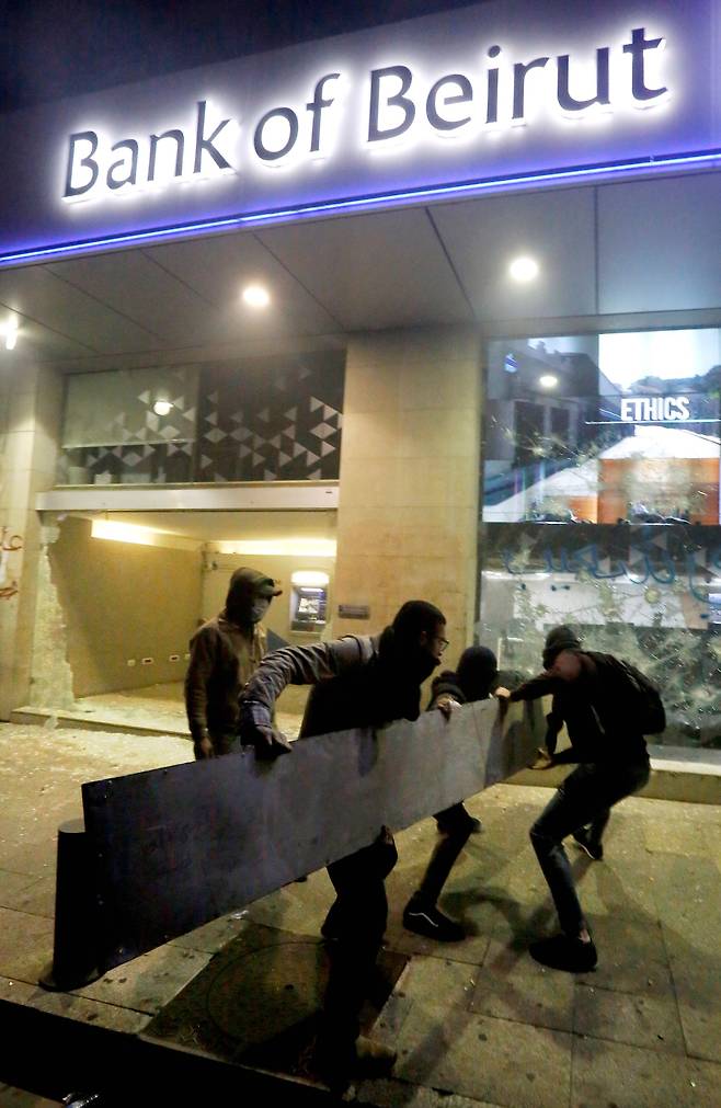 14일(현지시간) 레바논 수도 베이루트의 중심가 하므라 거리에서 반정부 시위대가 은행 창문을 부수고 있다. [AFP=연합뉴스]