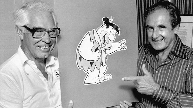 80년을 꾸준히 사랑 받는 캐릭터 ‘톰과 제리’를 만들어낸 빌 한나(왼족)와 조 바버라가 애니메이션 ‘플린트스톤’ 캐릭터 카드보드를 든 채 웃고 있다.AFP 자료사진